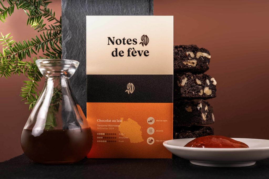 Une tablette de chocolat entourée de miel, d'une branche de sapin, de pâte de coing et de brownies