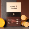 Une tablette de chocolat à l'emballage brun, entourée de pêche, de cassis, de canne à sucre